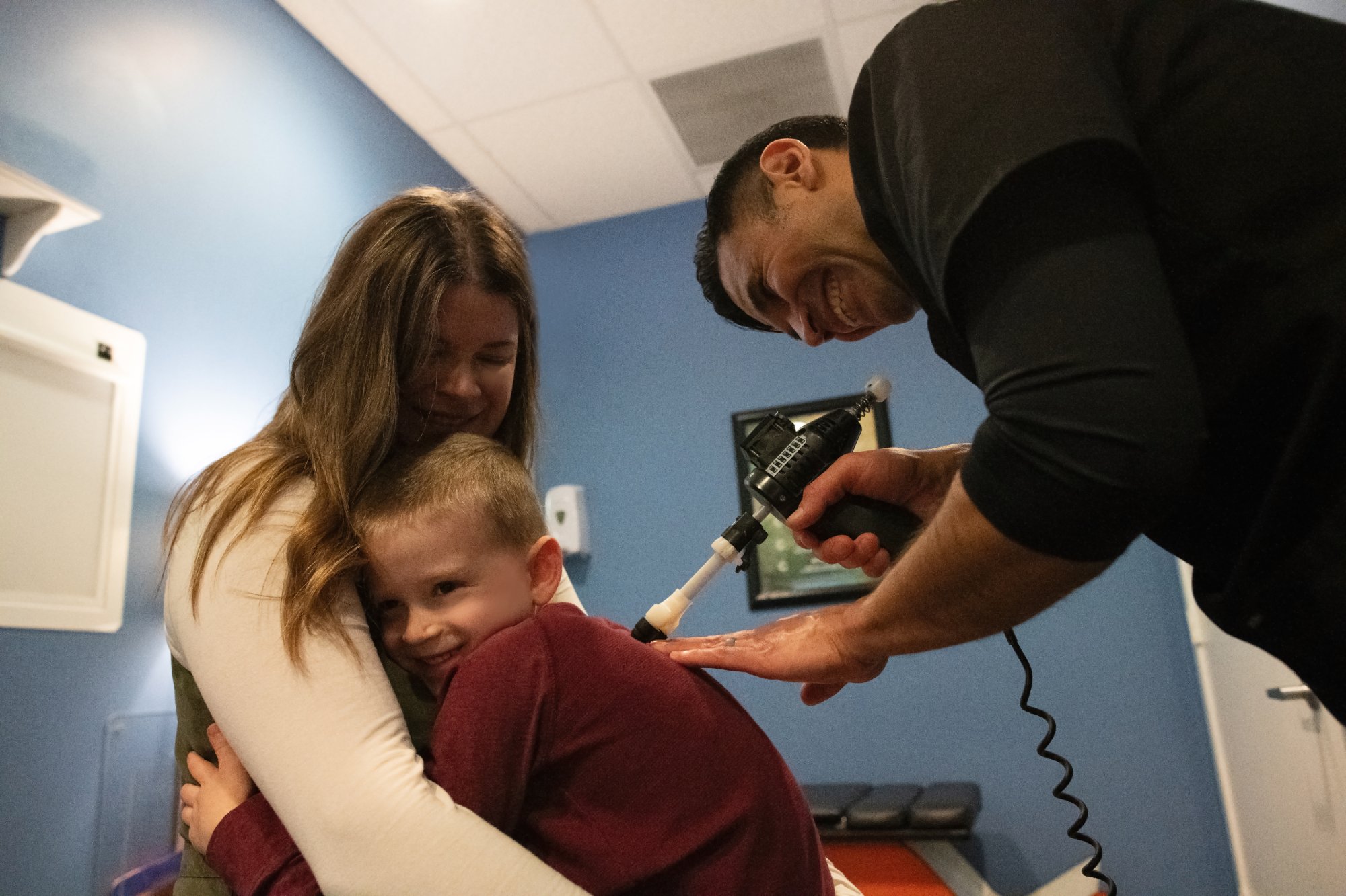 Dr. Posada treating a child held by a parent, all smiling